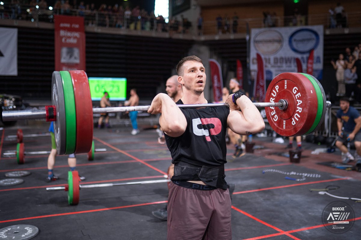 athlete holding a barbell with colorful plates on his shoulders